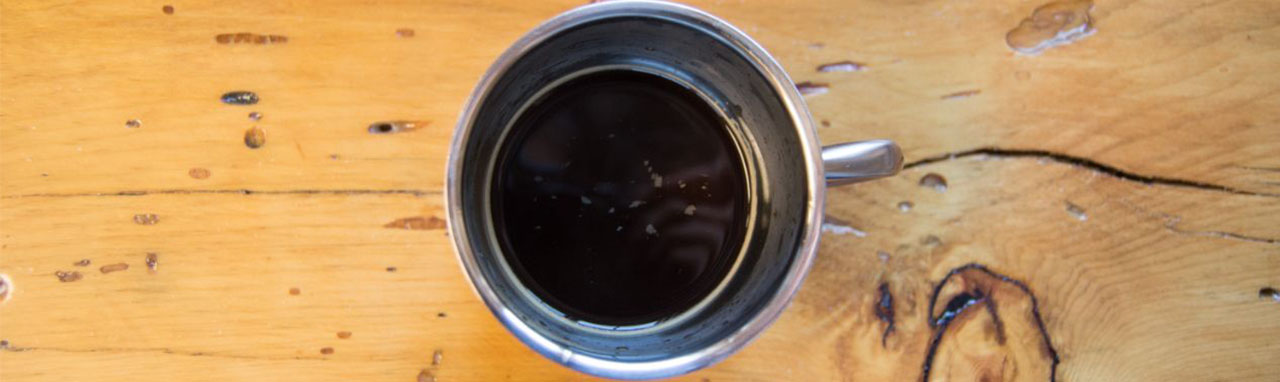 Une tasse de café noir sur une table en bois
