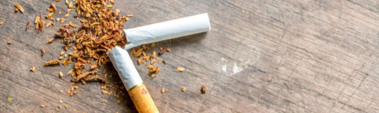 Une cigarette cassée en deux avec du tabac renversé à coté, sur une table en bois