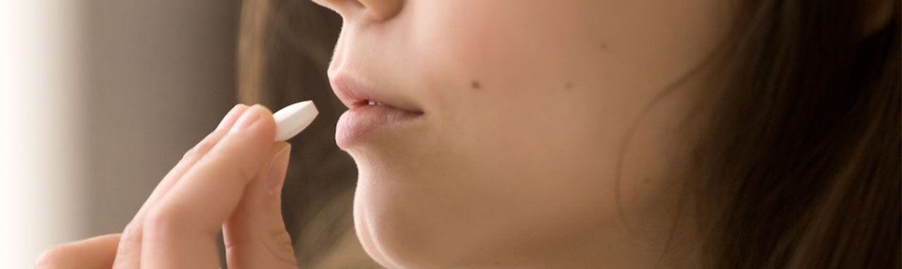 Une femme porte un comprimé à sucer à sa bouche
