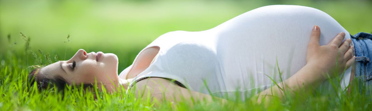 Une femme enceinte est allongée dans l'herbe