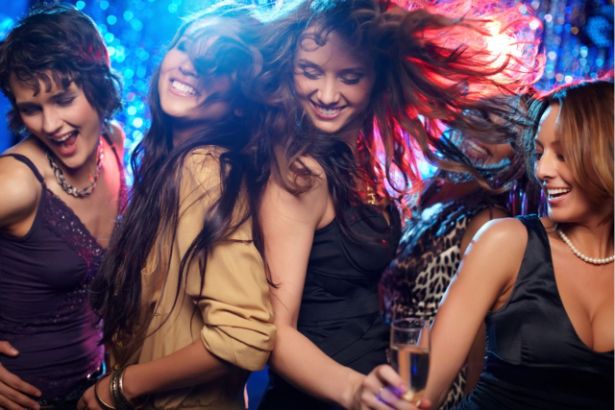 Un groupe de quatre jeunes femmes dansent dans une boite de nuit