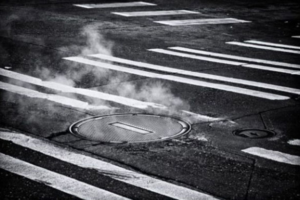 Une bouche d'égout fumante au milieu d'une route