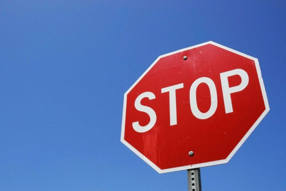 Un panneau de signalisation "STOP" devant un ciel bleu