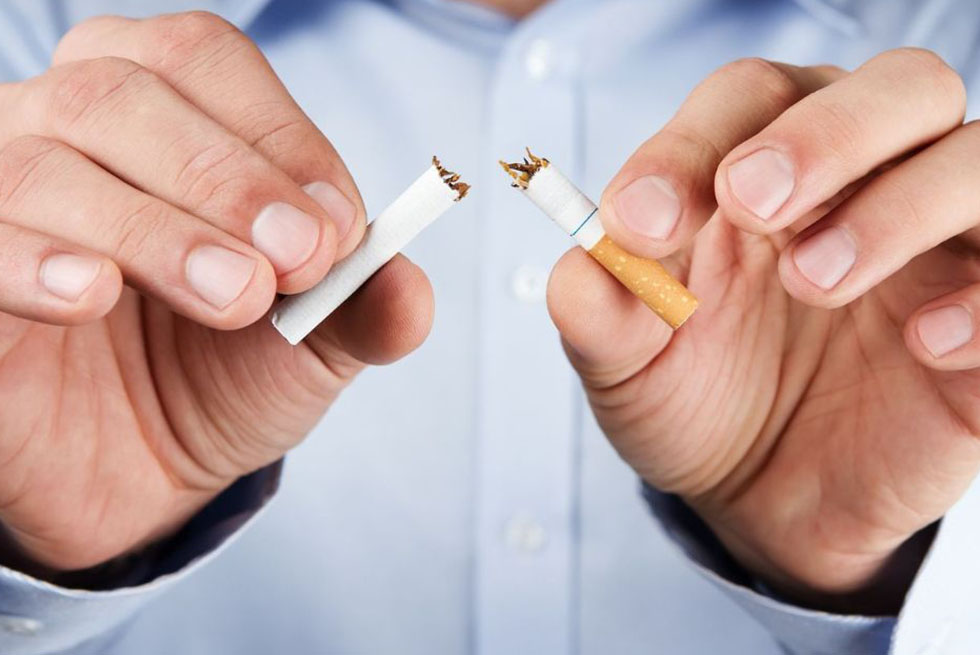Un homme en chemise tient une cigarette brisée entre ses doigts